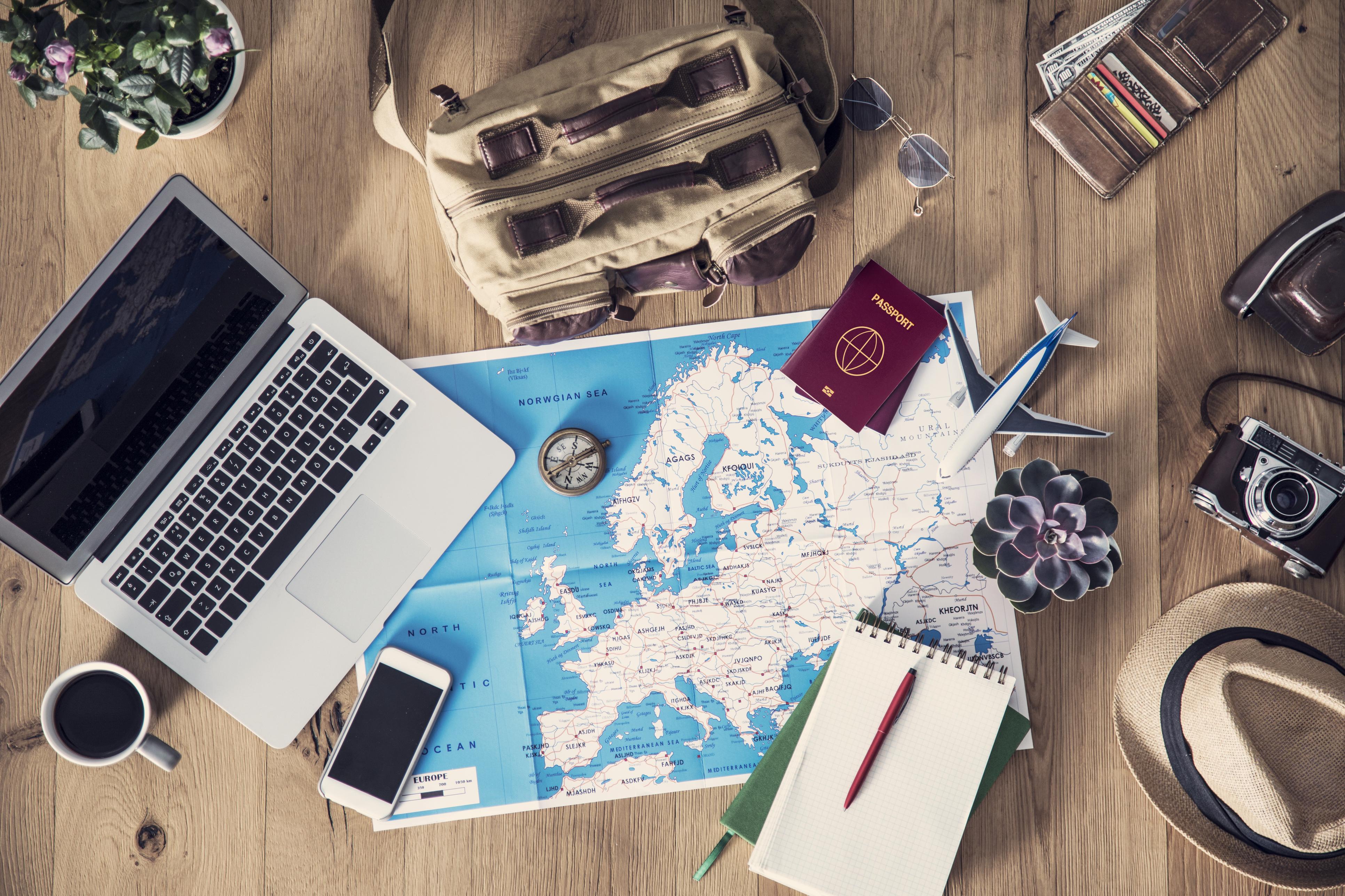 A laptop, passport, and Europe map laid out for travel and study planning